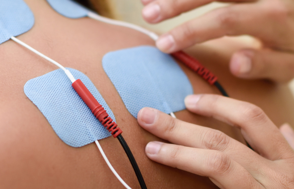 fisioterapeuta colocando electrodos en una sesion de fisioterapia en son rapinya